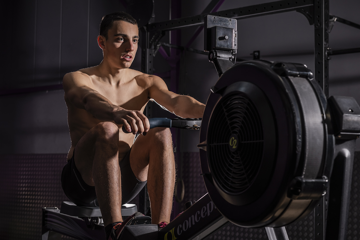 Un homme sur rameur concentré sur son moniteur.